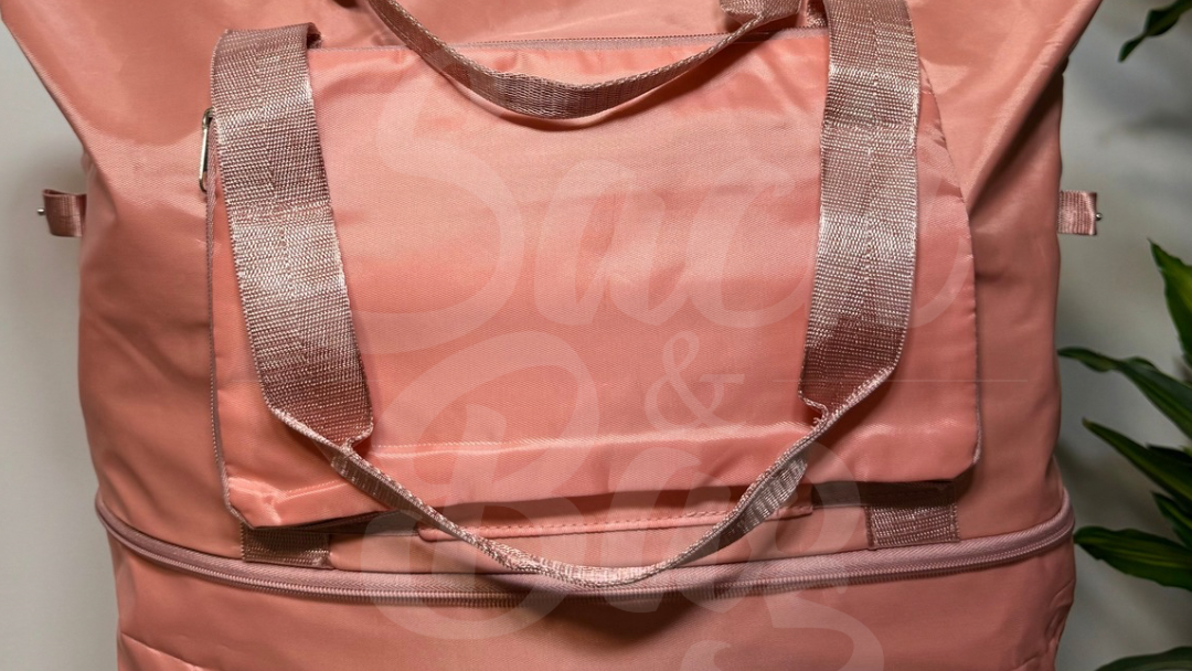 Vista frontal bolso viaje rosa plegable con compartimentos organizadores